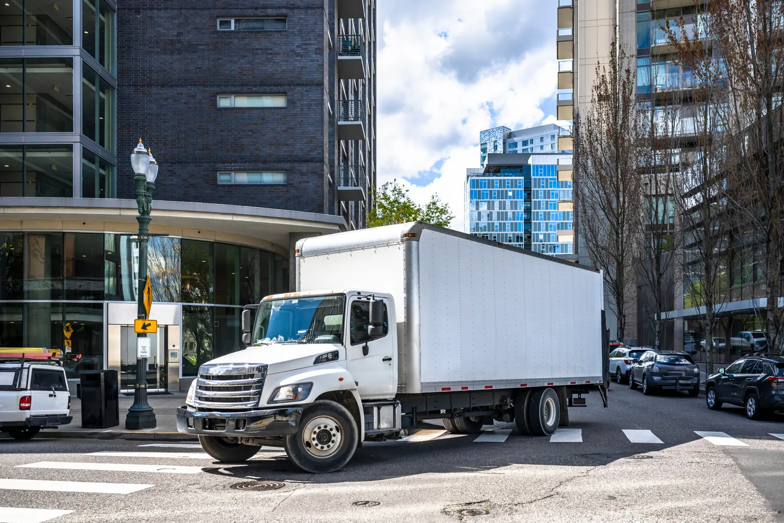 White commercial box truck crossing a city street.