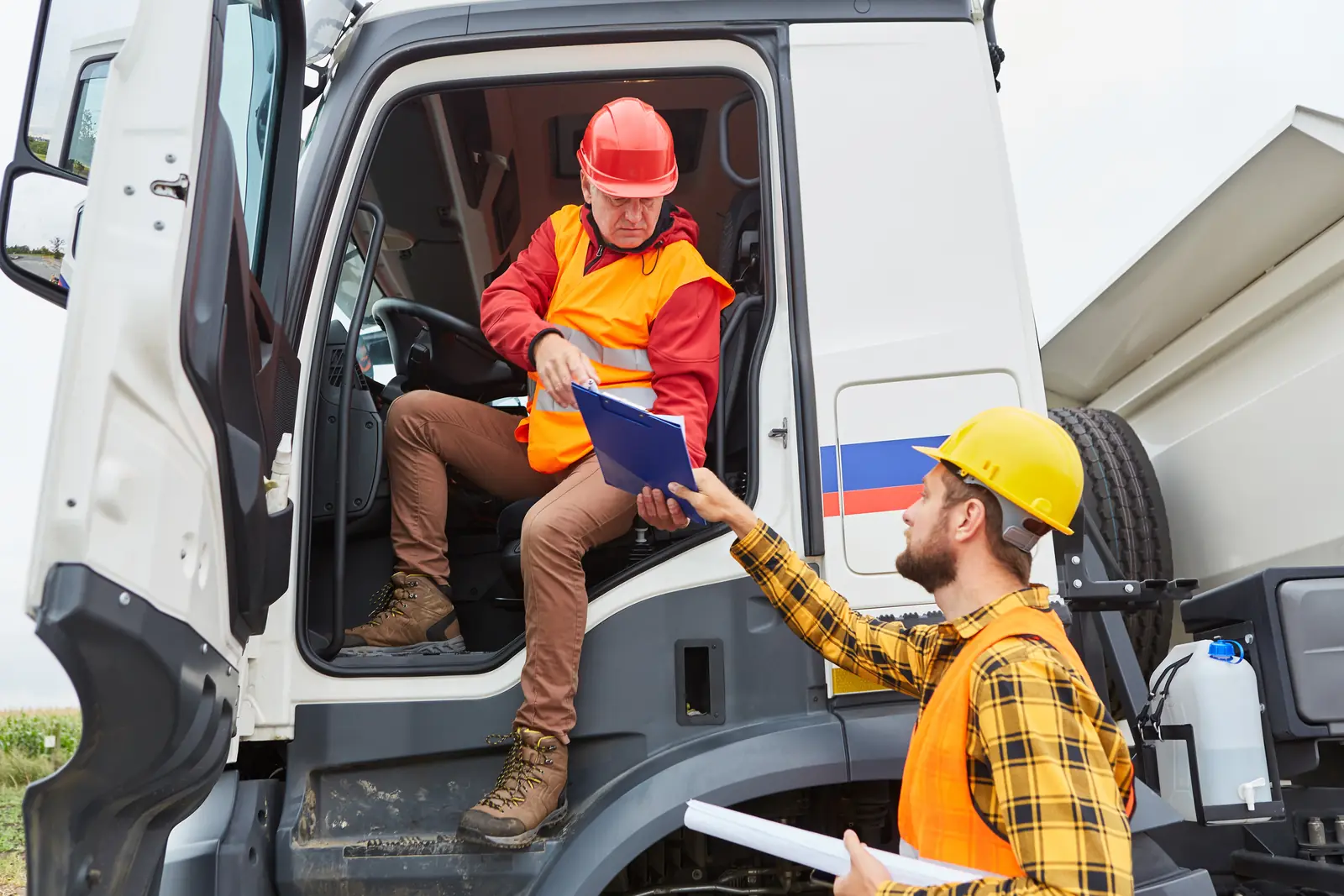 Two people review paperwork beside a commercial truck.
